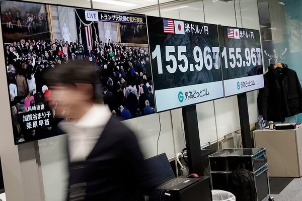 A staff member walks past a monitor showing Donald Trump delivering a speech at the inauguration ceremony as President of the United States, Tuesday, Jan. 21, 2025, at a foreign exchange trading company in Tokyo. (AP Photo/Eugene Hoshiko)