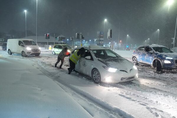 People help to push cars stuck in snow in Leeds, England, Sunday, Jan. 5, 2025. (Danny Lawson/PA via AP)