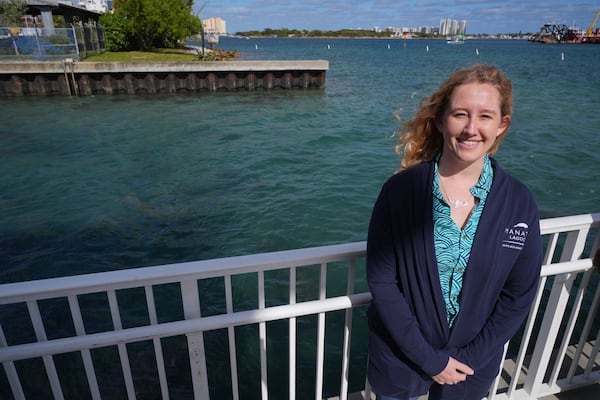 Rachel Shanker, education manager for Florida Power & Light Company's Manatee Lagoon, poses for a picture beside waters where dozens of manatees gather in winter in the warm-water outflows of the company's power plant, in Riviera Beach, Fla., Friday, Jan. 10, 2025. (AP Photo/Rebecca Blackwell)