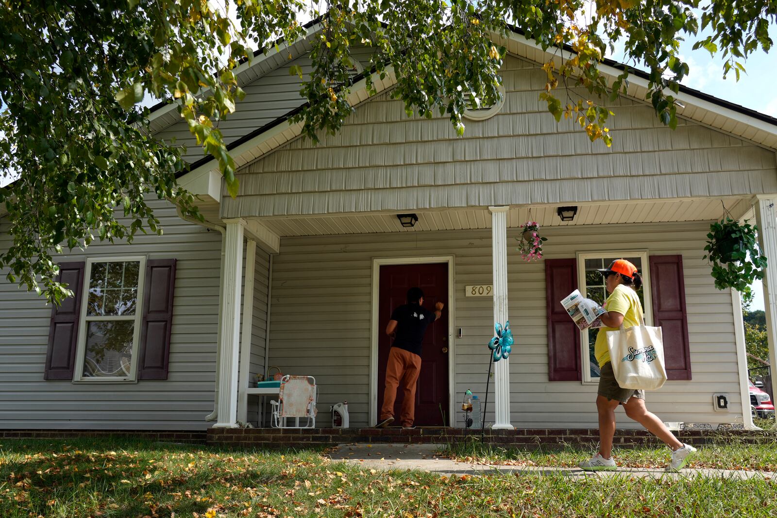 Salvador Fonseca knocks on a door with Elena Jimenez as they visit a home during a voter engagement event for the Latino community in Greensboro, N.C., Saturday, Sept. 21, 2024. (AP Photo/Chuck Burton)