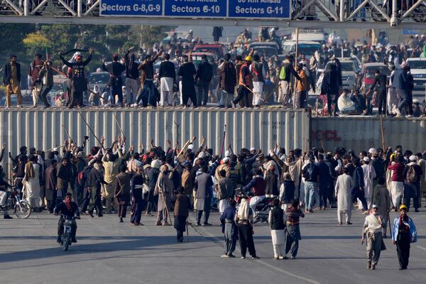 Supporters of imprisoned former premier Imran Khan's Pakistan Tehreek-e-Insaf party, gather to remove shipping containers to clear way for their rally demanding Khan's release, in Islamabad, Pakistan, Tuesday, Nov. 26, 2024. (AP Photo/Anjum Naveed)