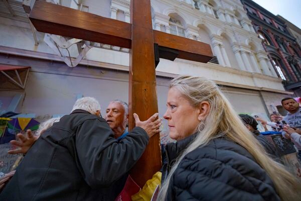 Louis Tenedorio, left, of Long Island, N.Y., hugs Dan Beazley of Northville, Mich., holding cross, as Linda Flick looks toward a memorial on Bourbon Street and Canal Street in New Orleans, Saturday, Jan. 4, 2025, where Flick's nephew and Tenedorio's son, Matthew Tenedorio, was killed in the New Year's Day attack. (AP Photo/Matthew Hinton)