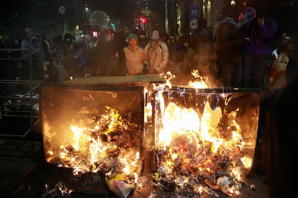 Demonstrators stand at a burning barricade during a rally to protest against the government's decision to suspend negotiations on joining the European Union in Tbilisi, Georgia, early Tuesday, Dec. 3, 2024. (AP Photo/Zurab Tsertsvadze)