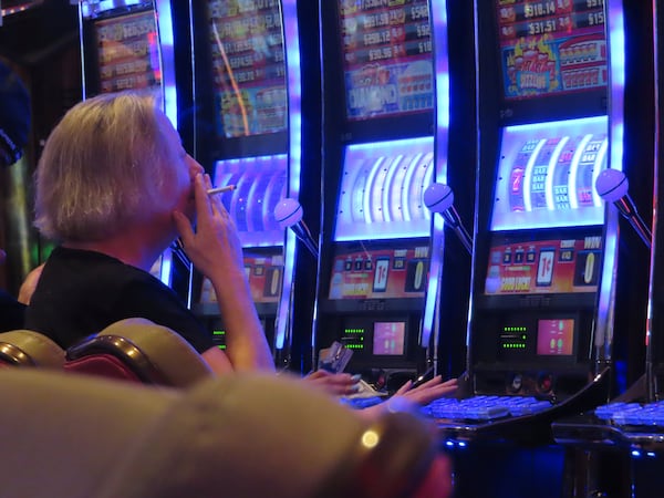 A gambler smokes while playing a slot machine at the Hard Rock casino in Atlantic City N.J. on Aug. 8, 2022. (AP Photo/Wayne Parry)