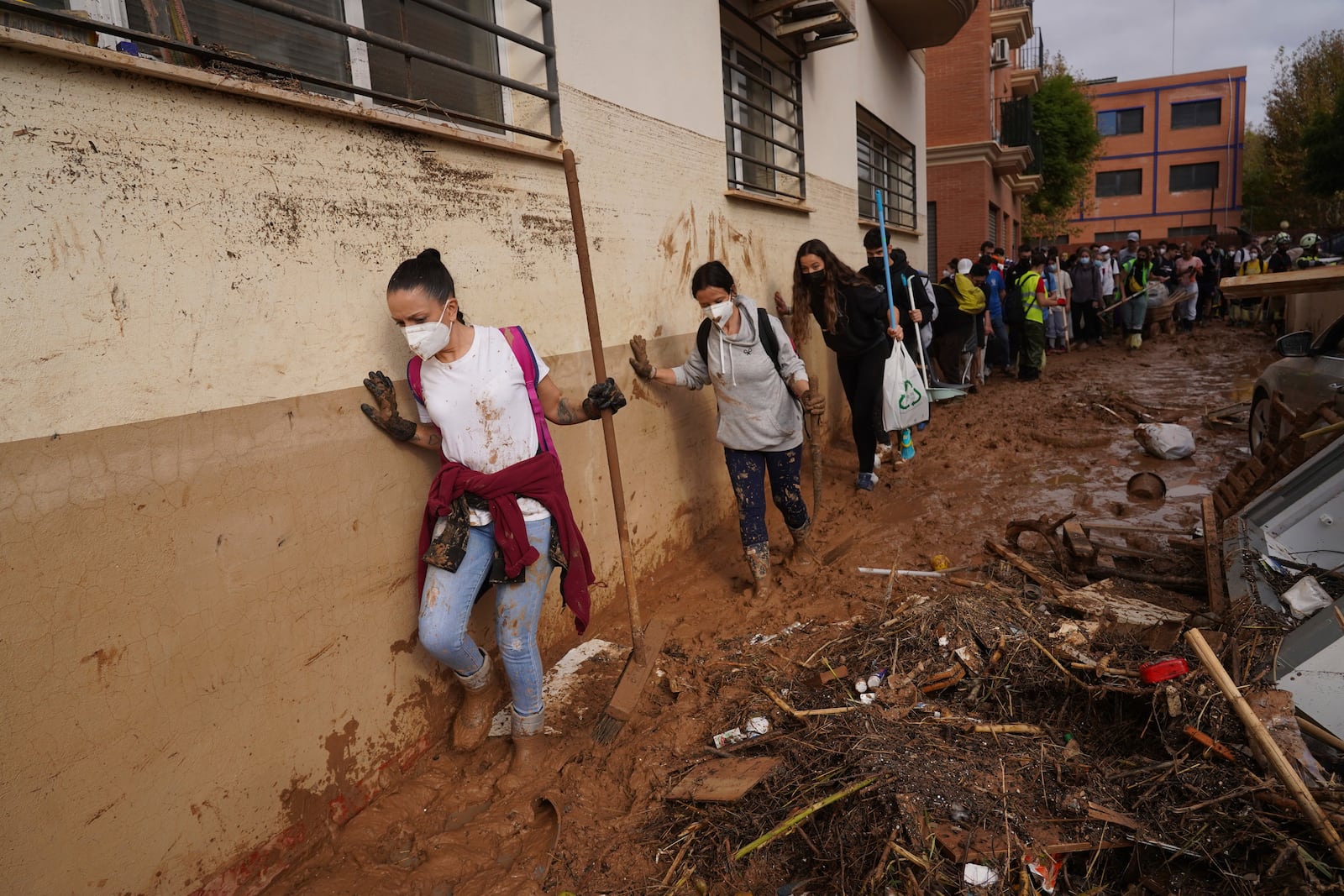 Volunteers walk in the mud to help with the clean up operation after floods in Massanassa, just outside of Valencia, Spain, Saturday, Nov. 2, 2024. (AP Photo/Alberto Saiz)