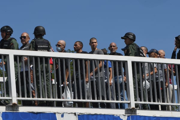 People detained during a government crackdown following anti-government protests against the results of the presidential election, are escorted by National Guardsmen across a pedestrian bridge upon their release from the prison in Tocuyito, Venezuela, Saturday, Nov. 16, 2024. (AP Photo/Jacinto Oliveros)