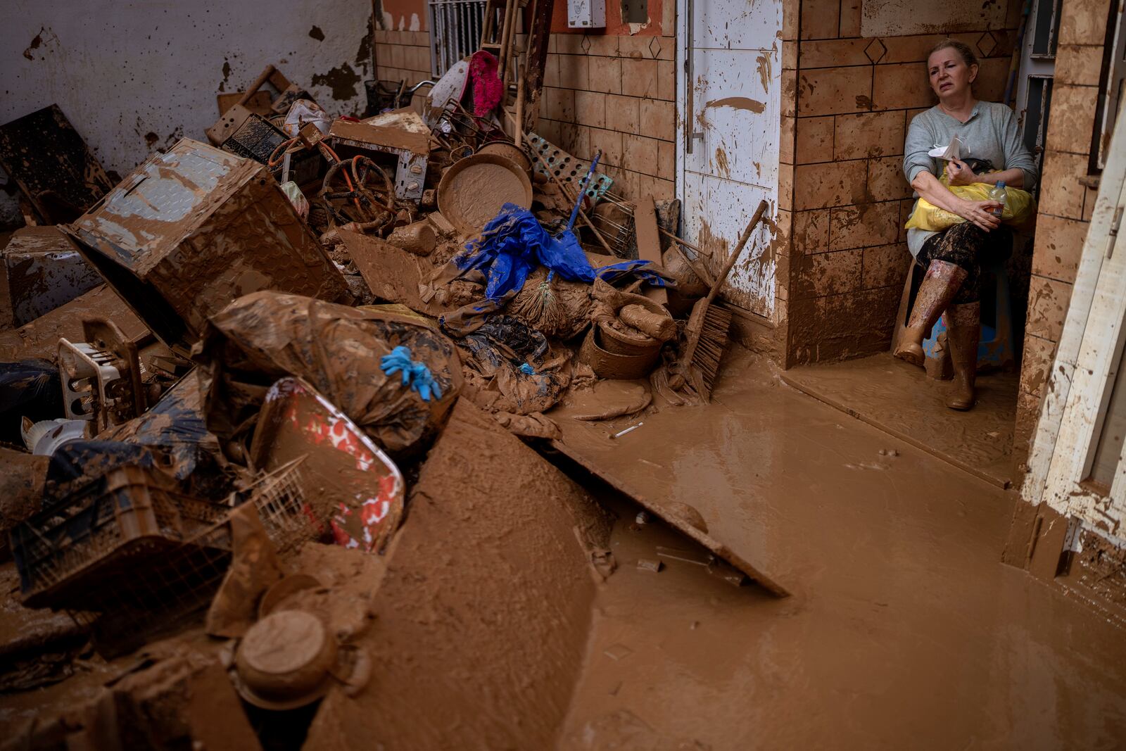 Dolores Merchan, 67, looks down on her mud-splattered belongings from the house where she has lived all her life with her husband and three children, and which has been severely affected by the floods in Masanasa, Valencia, Spain, Thursday, Nov. 7, 2024. (AP Photo/Emilio Morenatti)