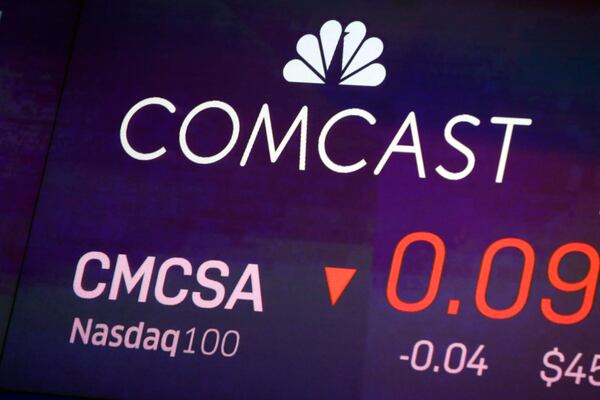 FILE - The symbol for Comcast appears on a screen at the Nasdaq MarketSite, on Oct. 1, 2019 in New York. (AP Photo/Richard Drew, File)