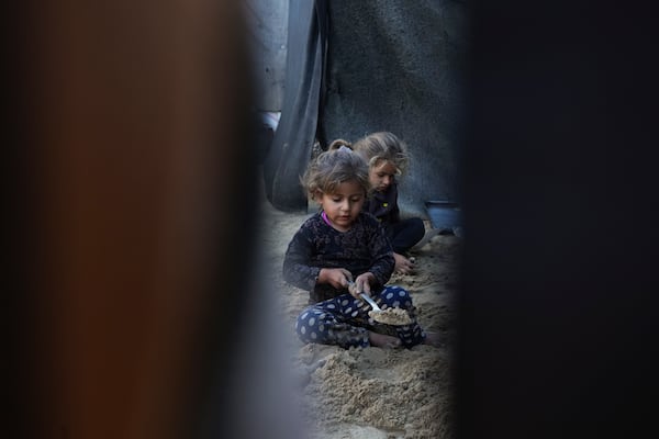 Grandchildren of Reda Abu Zarada, displaced from Jabaliya in northern Gaza, play with sand next to their tent at a camp in Khan Younis, Gaza Strip, Thursday, Dec. 19, 2024. (AP Photo/Abdel Kareem Hana)