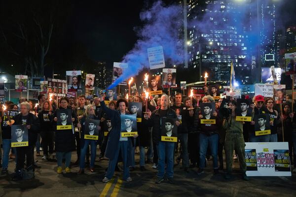 Demonstrators hold torches during a protest calling for the immediate release of the hostages held in the Gaza Strip by the Hamas militant group in Tel Aviv, Israel, on Monday, Jan. 13, 2025. (AP Photo/Ohad Zwigenberg)