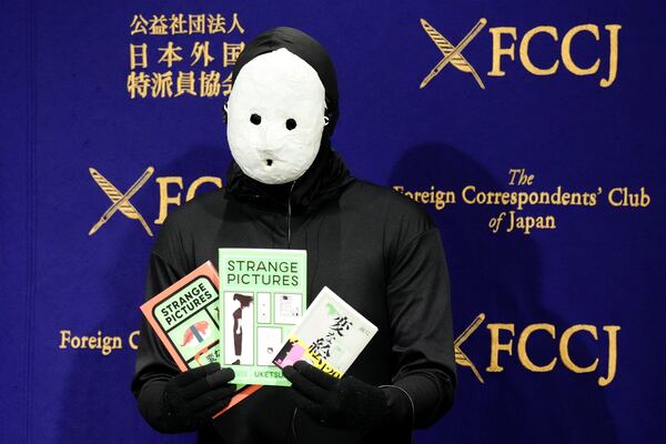 Uketsu, a Japanese YouTuber and horror author holds his books at his media conference at the Foreign Correspondents' Club of Japan, Thursday, Jan. 16, 2025, in Tokyo. (AP Photo/Eugene Hoshiko)