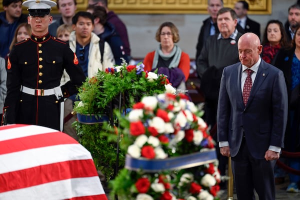 Sen. Mark Kelly, D-Ariz., right, pauses at the flag-draped casket of former President Jimmy Carter as he lies in state at the U.S. Capitol, Wednesday, Jan. 8, 2025, in Washington. (AP Photo/John McDonnell)