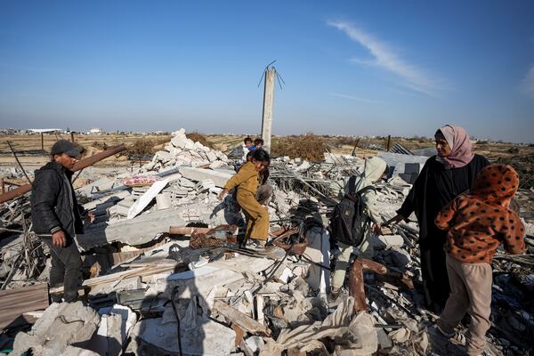 Members of the Abu Sheiban family salvage what they can of their belongings from under rubble of their destroyed home, days after the ceasefire deal between Israel and Hamas, in Rafah, southern Gaza Strip, Tuesday, Jan. 21, 2025. (AP Photo/Abdel Kareem Hana)