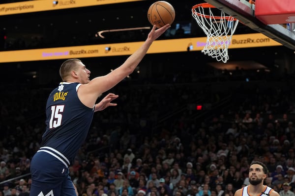 Denver Nuggets center Nikola Jokic scores on Phoenix Suns guard Tyus Jones during the first half of an NBA basketball game, Wednesday, Dec. 25, 2024, in Phoenix. (AP Photo/Rick Scuteri)