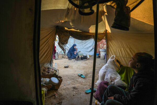 Alaa Hamami prepares a meal while her 10-year-old daughter, Basant, sits inside their tent at a camp for displaced Palestinians in Deir al-Balah, Gaza Strip, Nov. 7, 2024. (AP Photo/Abdel Kareem Hana)