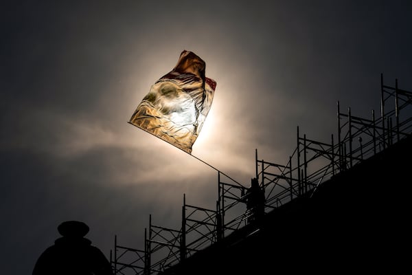 A man perched on the roof of a building waves the Romanian flag during a rally organized by the right wing Alliance for the Unity of Romanians (AUR), calling for free elections after Romania' s Constitutional Court annulled the first round of presidential elections last December, in Bucharest, Romania, Sunday, Jan. 12, 2025. (AP Photo/Vadim Ghirda)