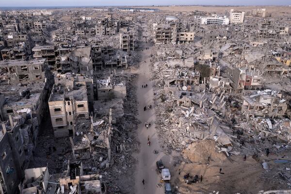 An aerial photograph taken by a drone shows Palestinians walking through the destruction caused by the Israeli air and ground offensive, in Rafah, Gaza Strip, Tuesday, Jan. 21, 2025. (AP Photo/Mohammad Abu Samra)