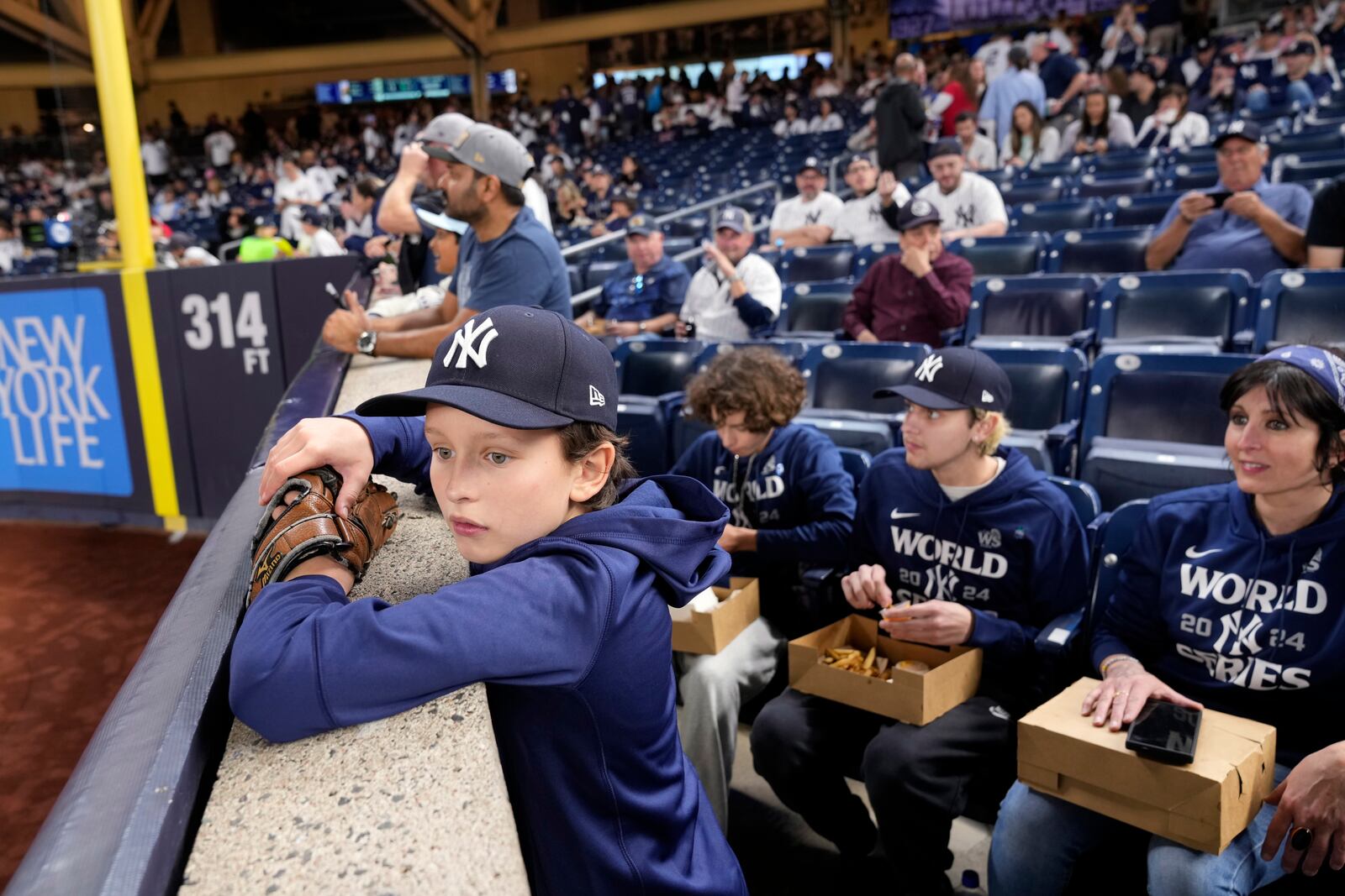 Everett Teel-Young, 11, watches batting practice along with his mother and brothers before Game 5 of the baseball World Series between the Los Angeles Dodgers and New York Yankees, Wednesday, Oct. 30, 2024, in New York. The family was given tickets from the New York Yankees to sit in the section where fans were ejected during Game 4 after interfering with Los Angeles Dodgers' Mookie Betts as he made a catch.(AP Photo/Seth Wenig)