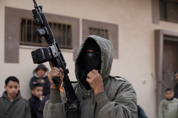 A Palestinian gunman attends the funeral of Muhammad Hamarsheh, 13, and Ahmad Zaid, 20, killed during an Israeli military raid in the village of Yabad near the West Bank city of Jenin, Monday, Nov. 25, 2024. (AP Photo/Majdi Mohammed)