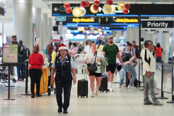 An American Airlines employee wearing a Santa Claus hat walks through the American terminal at Miami International Airport, on Christmas Eve, Tuesday, Dec. 24, 2024, in Miami. (AP Photo/Rebecca Blackwell)