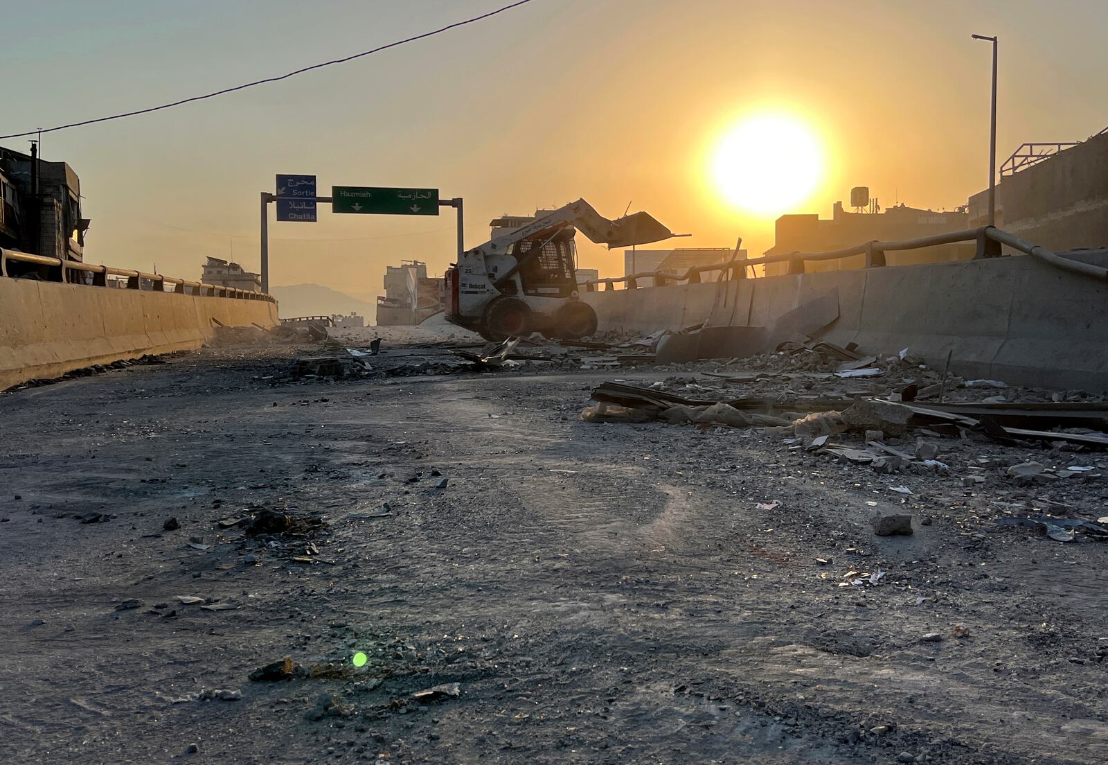 A municipality worker uses a skid steer loader to reopen a bridge closed by the rubble of a destroyed building that was hit by an Israeli airstrike on Dahiyeh, as the sunrise in the southern suburb of Beirut, Lebanon, Friday, Nov. 1, 2024. (AP Photo/Hussein Malla)