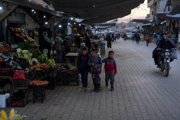 Children walk past goods for sale at an open market in Atareb, northern the city of Aleppo, Syria, Sunday, Dec. 15, 2024. (AP Photo/Khalil Hamra)