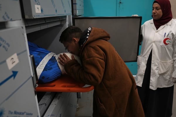 A youth takes the last look at the bodies of four Palestinians killed after there vehicle was targeted by an Israeli airstrike in the refugee camp of Tulkarem on Thursday, in the morgue of a local hospital ahead of their funeral in the West Bank city of Tulkarem Friday, Dec.20, 2024. (AP Photo/Nasser Nasser)