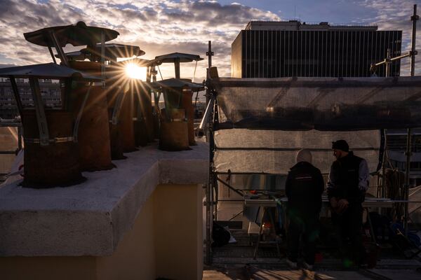 Roofers work on a building in Paris, Wednesday, Nov. 20, 2024. (AP Photo/Louise Delmotte)