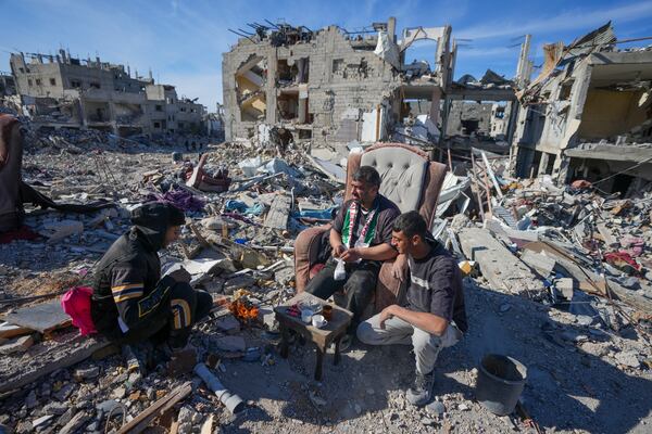 Hussein Barakat sits on a couch with two others, atop the rubble of his destroyed home a day after the ceasefire deal between Israel and Hamas came into effect, in Rafah, southern Gaza Strip, Monday, Jan. 20, 2025,(AP Photo/Abdel Kareem Hana)