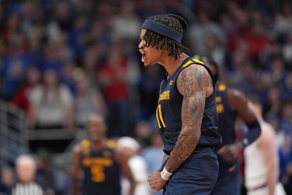 West Virginia guard Jonathan Powell celebrates after making a basket during the first half of an NCAA college basketball game against Kansas, Tuesday, Dec. 31, 2024, in Lawrence, Kan. (AP Photo/Charlie Riedel)