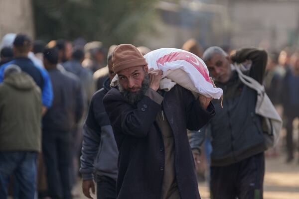 A man carries a sack of donated flour at a UNRWA distribution center in the Nuseirat refugee camp, Gaza Strip, Tuesday Dec. 3, 2024.(AP Photo/Abdel Kareem Hana)