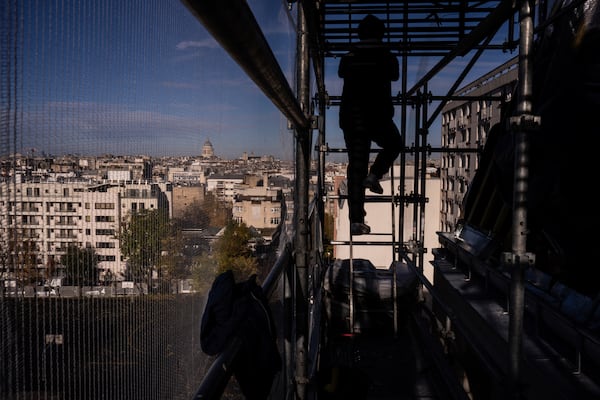 A roofer works on a building in Paris, Friday, Oct. 22, 2024. (AP Photo/Louise Delmotte)