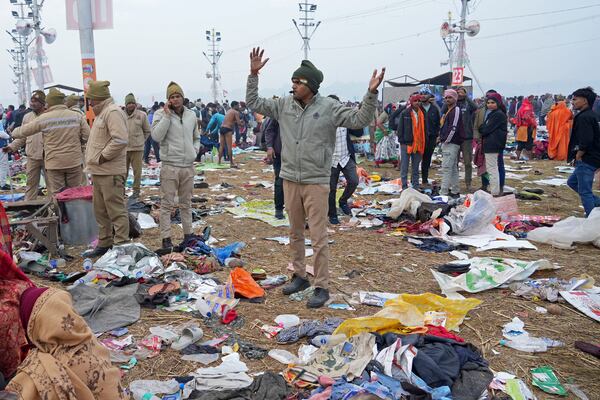 A policeman gestures as the belongings of Hindu devotees lie scattered after a stampede when Hindu devotees rushed to take a holy bath in the Sangam, the confluence of the Ganges, the Yamuna and the mythical Saraswati rivers, on "Mauni Amavasya" or new moon day during the Maha Kumbh festival in Prayagraj, India, Wednesday, Jan. 29, 2025. (AP Photo/Deepak Sharma)