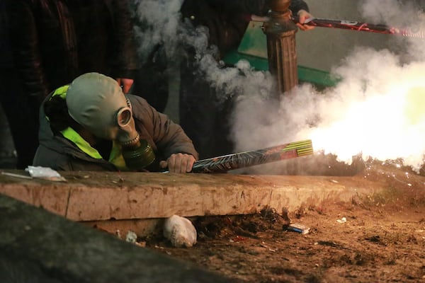 A demonstrator fires a firecracker towards police during a rally against the government's decision to suspend negotiations on joining the European Union for four years, outside the parliament's building in Tbilisi, Georgia, early Sunday, Dec. 1, 2024. (AP Photo/Zurab Tsertsvadze)