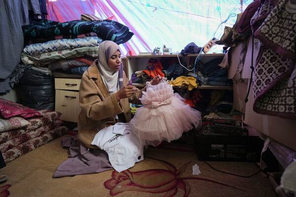 Areej al Qadi shows dress of her daughter Laila at her tent in a refugee camp in Deir al-Balah, Gaza Strip, Thursday Nov. 21, 2024. Seven-year-old Hamza, his five-year-old brother Abdelaziz, and his four-year-old sister Laila Hassan were among 9 people killed by an Israeli strike in Khan Younis on Wednesday. Palestinian health officials say the death toll in the Gaza Strip from the 13-month-old war between Israel and Hamas has surpassed 44,000. (AP Photo/Abdel Kareem Hana)