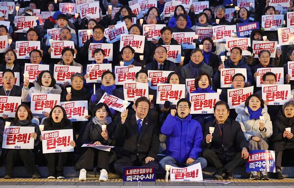 South Korea's main opposition Democratic Party leader Lee Jae-myung, bottom center left, and his party members stage a rally against the President Yoon Suk Yeol at the National Assembly in Seoul, South Korea, Wednesday, Dec. 4, 2024. The signs read "Yoon Suk Yeol should resign." (Ryu Hyung-seok/Yonhap via AP)