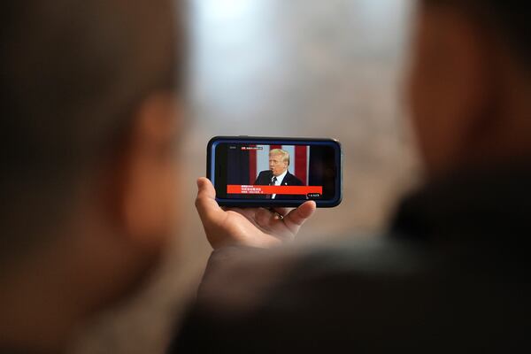 FILE - Li Chuanliang, left, and Pastor Pan Yongguang, part of a group of Chinese Christians resettled in Texas and awaiting final approval of their refugee status, watch a Chinese-captioned live broadcast of President Donald Trump speaking at his inauguration on a cell phon, Jan. 20, 2025, in Midland, Texas. (AP Photo/Rebecca Blackwell, File)