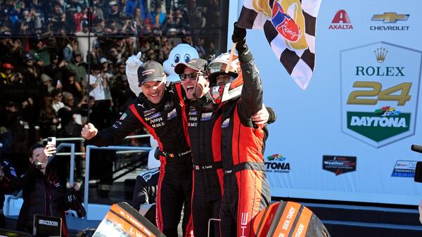 Porsche Penske Motorsports team winners, from left to right, Belgium's Laurens Vanthoor, Britain's Nick Tandy and Brazil's Felipe Nasr celebrate in Victory Lane after winning the IMSA Rolex 24 hour auto race at Daytona International Speedway, Sunday, Jan. 26, 2025, in Daytona Beach, Fla. (AP Photo/John Raoux)