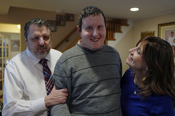 Dov Marcus smiles flanked by his parents, Robert Marcus and Debbie Marcus, in Teaneck, N.J., on Friday, Dec. 20, 2024. (AP Photo/Luis Andres Henao)