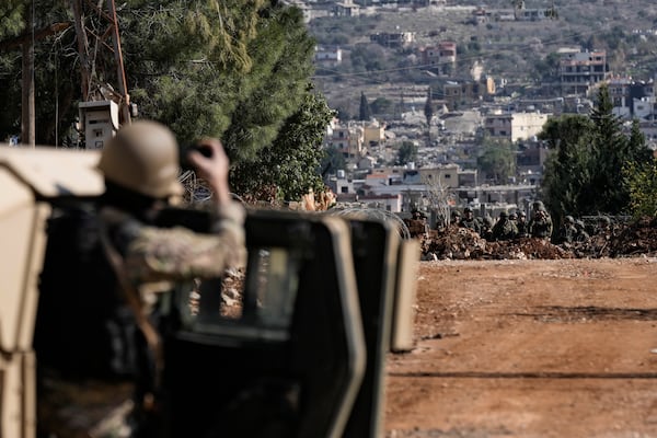 A Lebanese soldier filming as Israeli soldiers block a road in the southern Lebanese village of Aitaroun, Lebanon, Monday, Jan. 27, 2025. (AP Photo/Bilal Hussein)