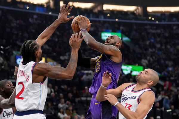 Los Angeles Lakers forward LeBron James, center, shoots as Los Angeles Clippers forward Kawhi Leonard, second from left, and forward Nicolas Batum defend during the first half of an NBA basketball game, Sunday, Jan. 19, 2025, in Inglewood, Calif. (AP Photo/Mark J. Terrill)