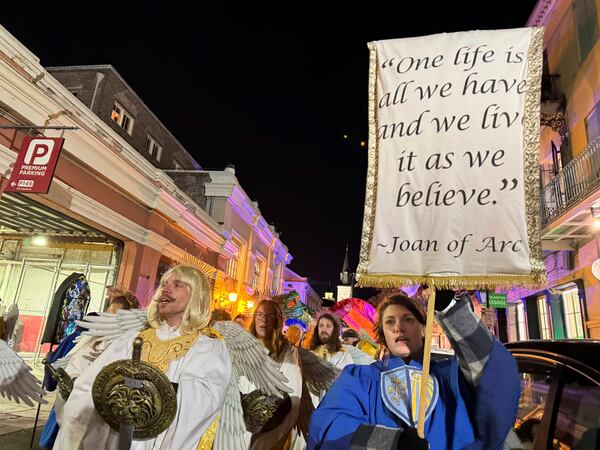 Marchers in the Joan of Arc parade on Monday, Jan. 6, 2025, in New Orleans, hold aloft a banner with a quote from the French saint. (AP Photo/Jack Brook)