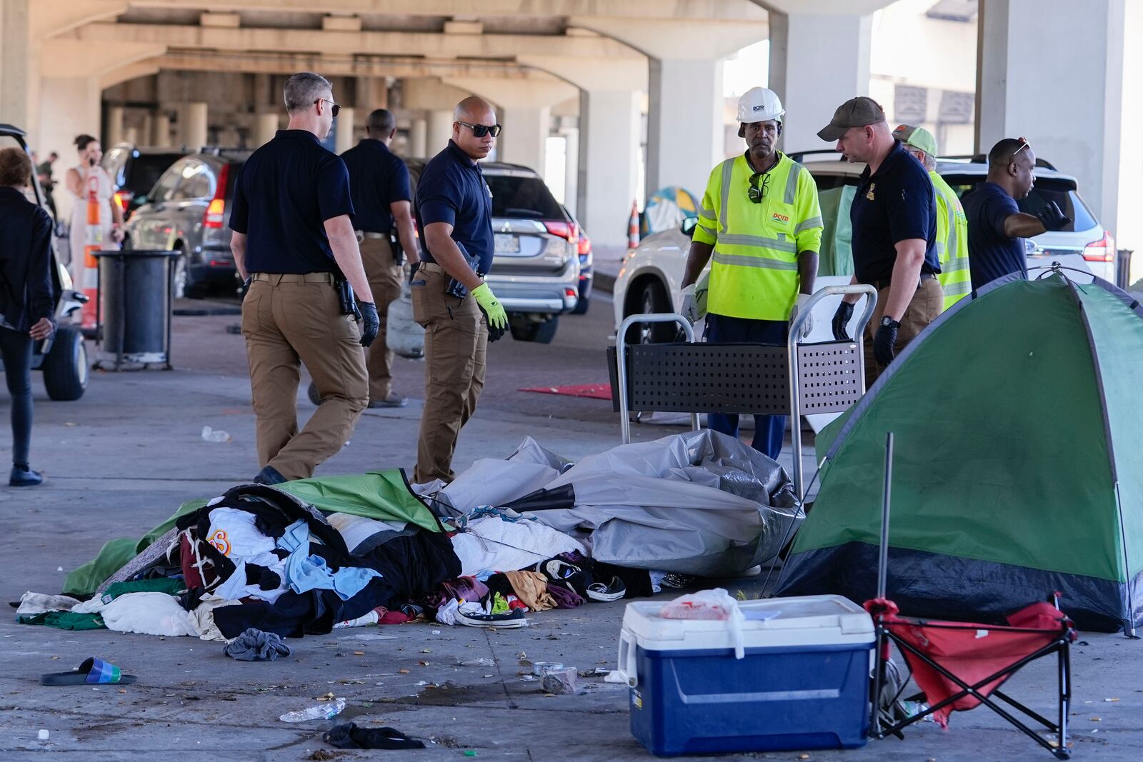 Louisiana State police give instructions to people living in a homeless encampment to move to a different pre-designated location as they perform a sweep in advance of a Taylor Swift concert in New Orleans, Wednesday, Oct. 23, 2024. (AP Photo/Gerald Herbert)