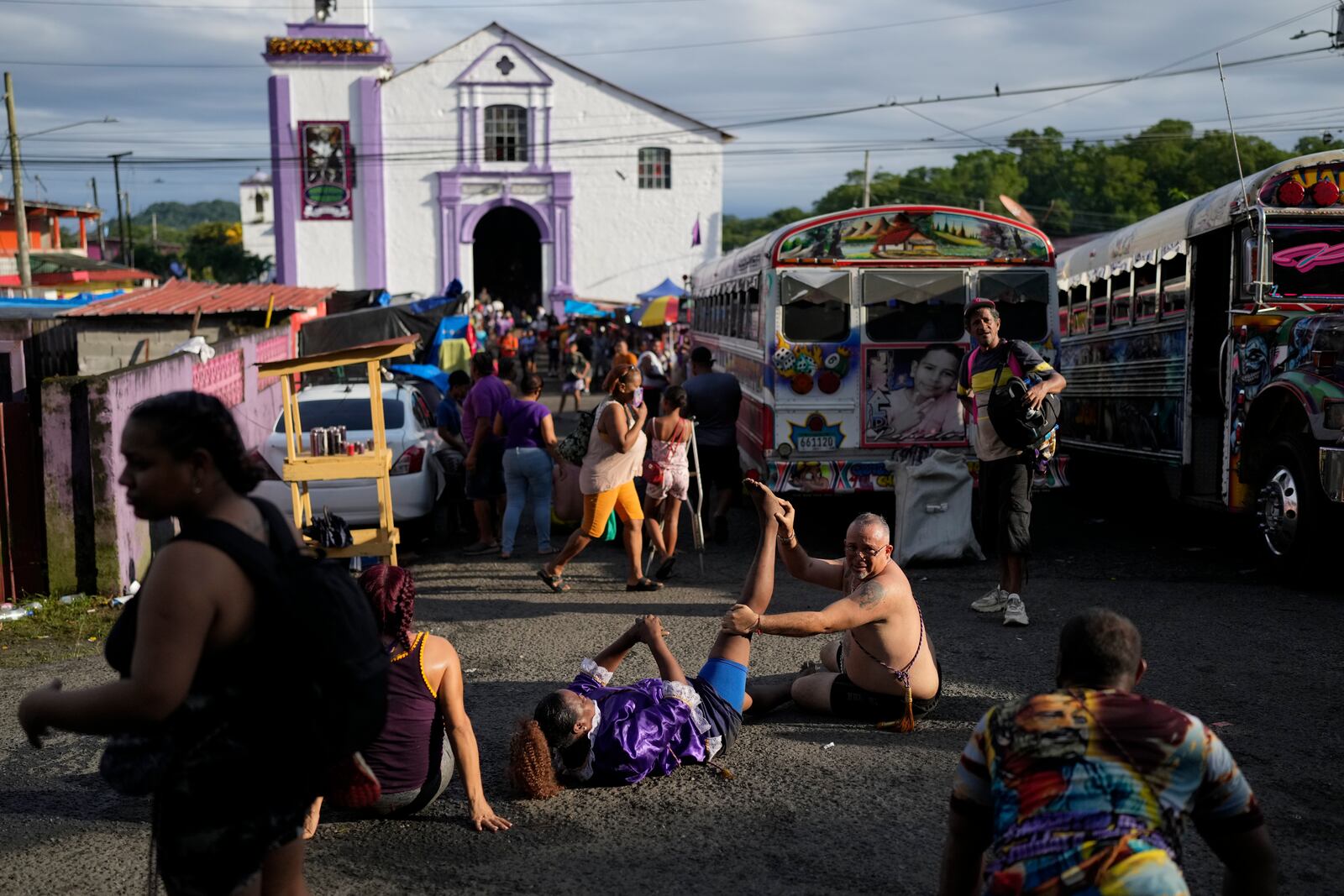 Pilgrim Ernesto Troya stretches his friend's leg as they take a break from crawling on their knees to San Felipe Church to honor the Black Christ in Portobelo, Panama, Monday, Oct. 21, 2024, during a festival celebrating the iconic statue that was found on the shore in 1658. (AP Photo/Matias Delacroix)