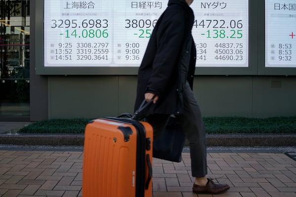 A person walks in front of an electronic stock board showing Japan's Nikkei, New York Dows and Shanhai indexes at a securities firm Friday, Nov. 29, 2024, in Tokyo. (AP Photo/Eugene Hoshiko)