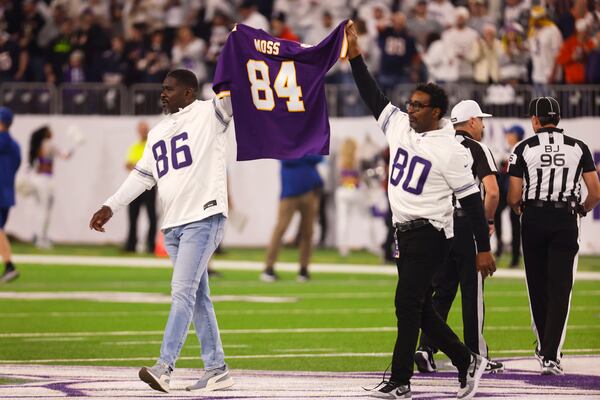 Formers Minnesota Vikings players Jake Reed, left, and Cris Carter carry a jersey for former Vikings wide receiver Randy Moss before an NFL football game against the Chicago Bears, Monday, Dec. 16, 2024, in Minneapolis. (AP Photo/Bruce Kluckhohn)