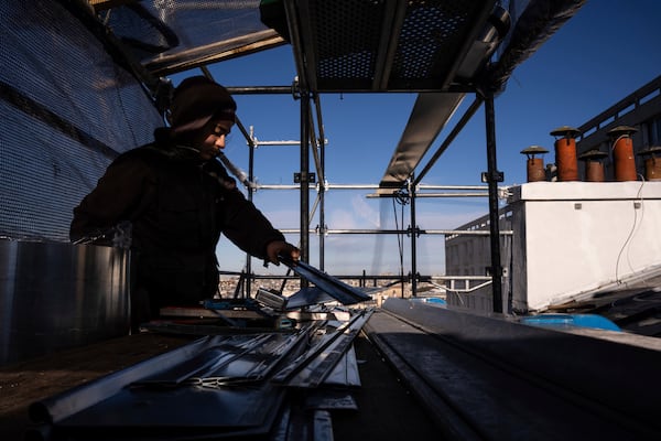 Fantine Dekens, 21, cuts zinc sheets on the roof of a building in Paris, Wednesday, Nov. 20, 2024. (AP Photo/Louise Delmotte)