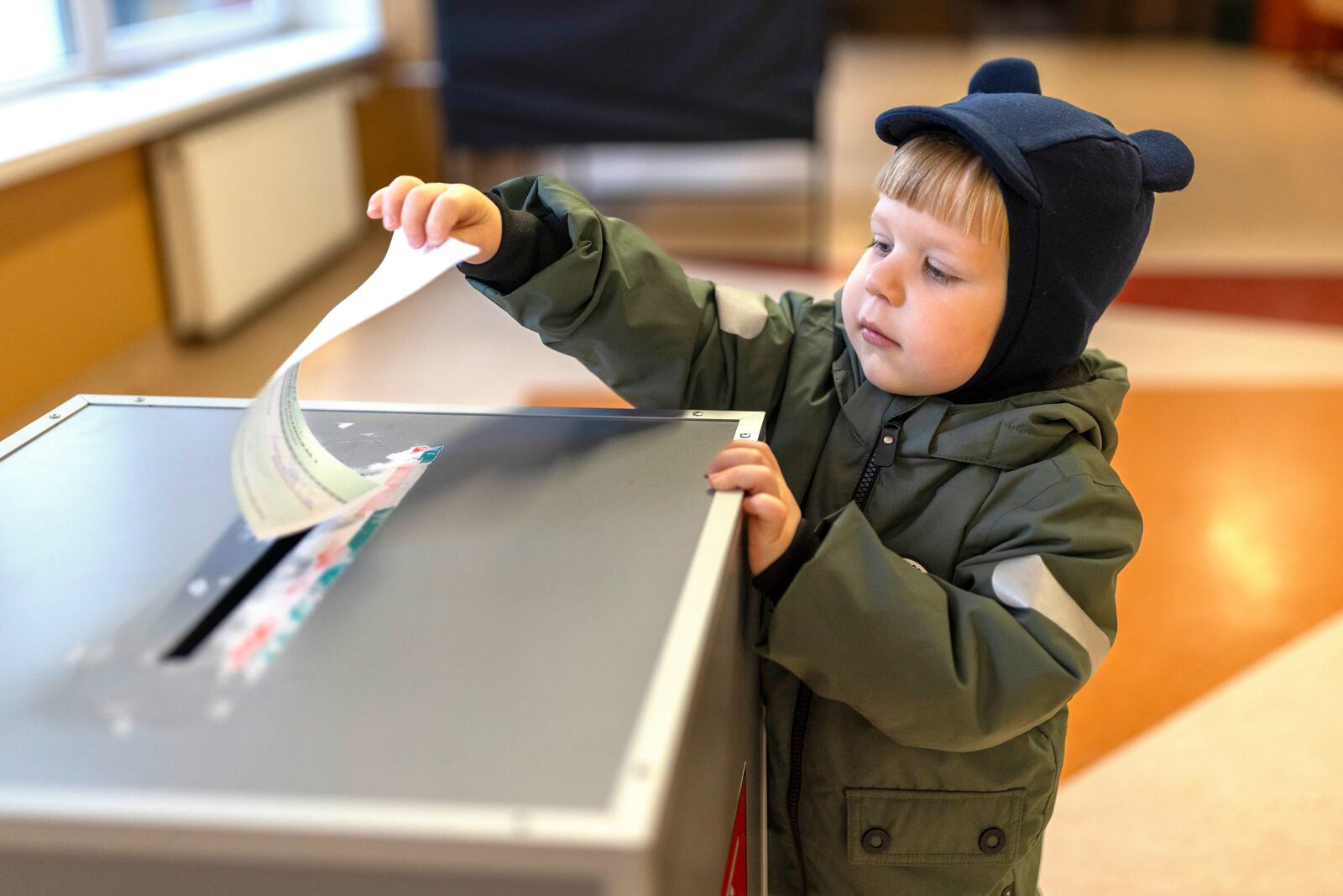 A boy helps to cast a ballot at a polling station during a second round of voting in parliamentary election, in Vilnius, Lithuania, Sunday, Oct. 27, 2024. (AP Photo/Mindaugas Kulbis)