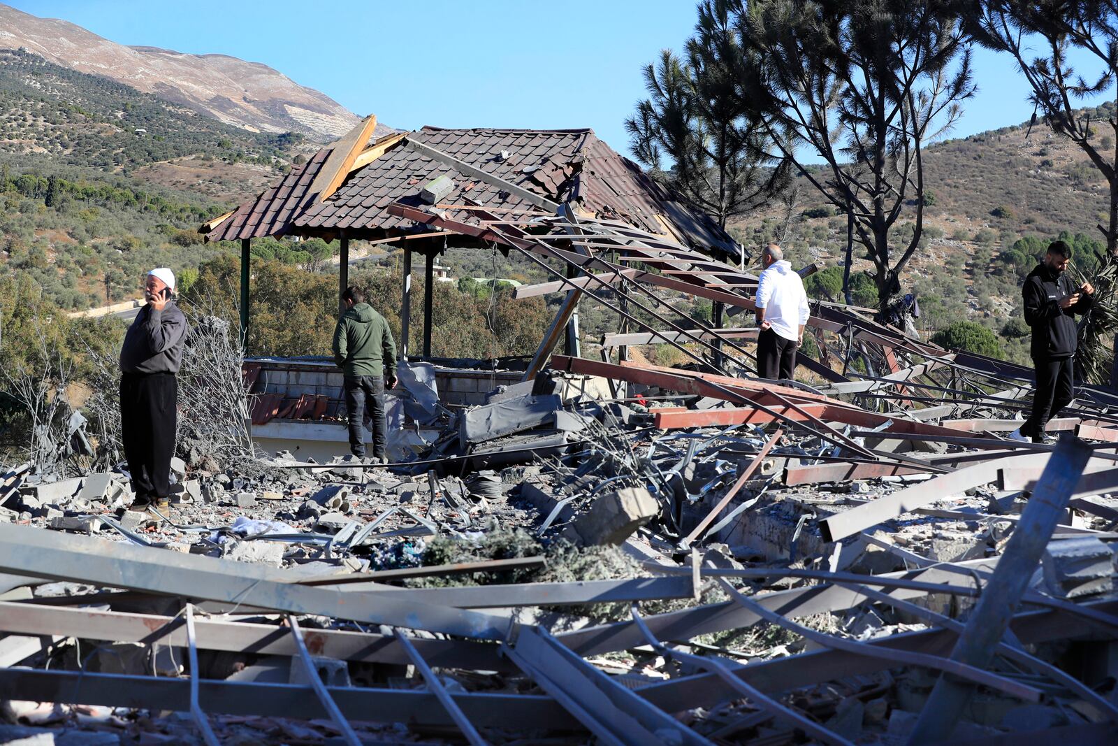 People observe the site where an Israeli airstrike hit a compound housing journalists, killing three media staffers from two different news agencies according to Lebanon's state-run National News Agency, in Hasbaya village, southeast Lebanon, Friday, Oct. 25, 2024. (AP Photo/Mohammed Zaatari)