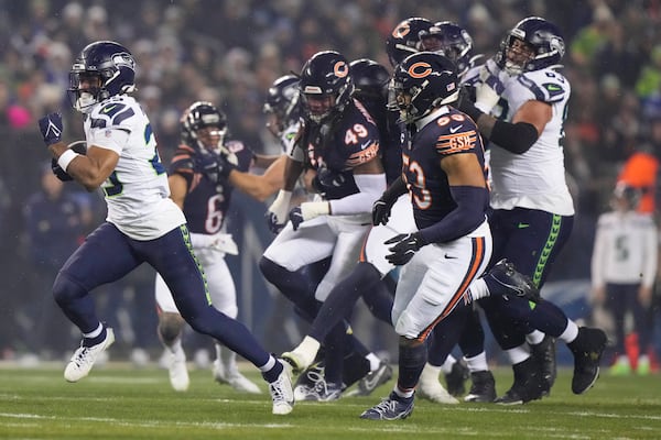 Seattle Seahawks running back Kenny McIntosh, left, runs for yardage against the Chicago Bears during the first half of an NFL football game, Thursday, Dec. 26, 2024, in Chicago. (AP Photo/Nam Y. Huh)